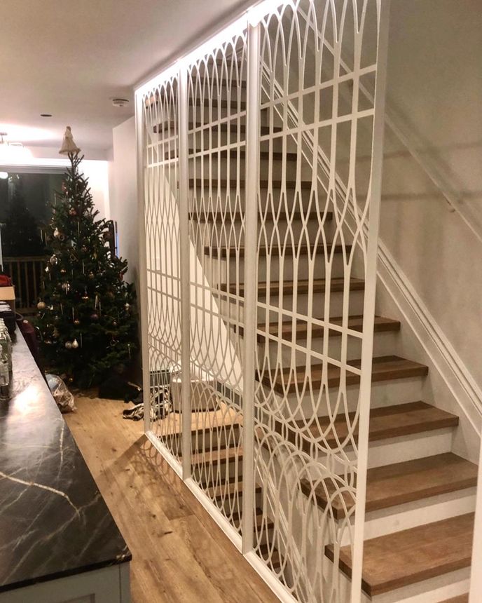 Custom ornamental metal screen partition with curved lattice pattern alongside a staircase