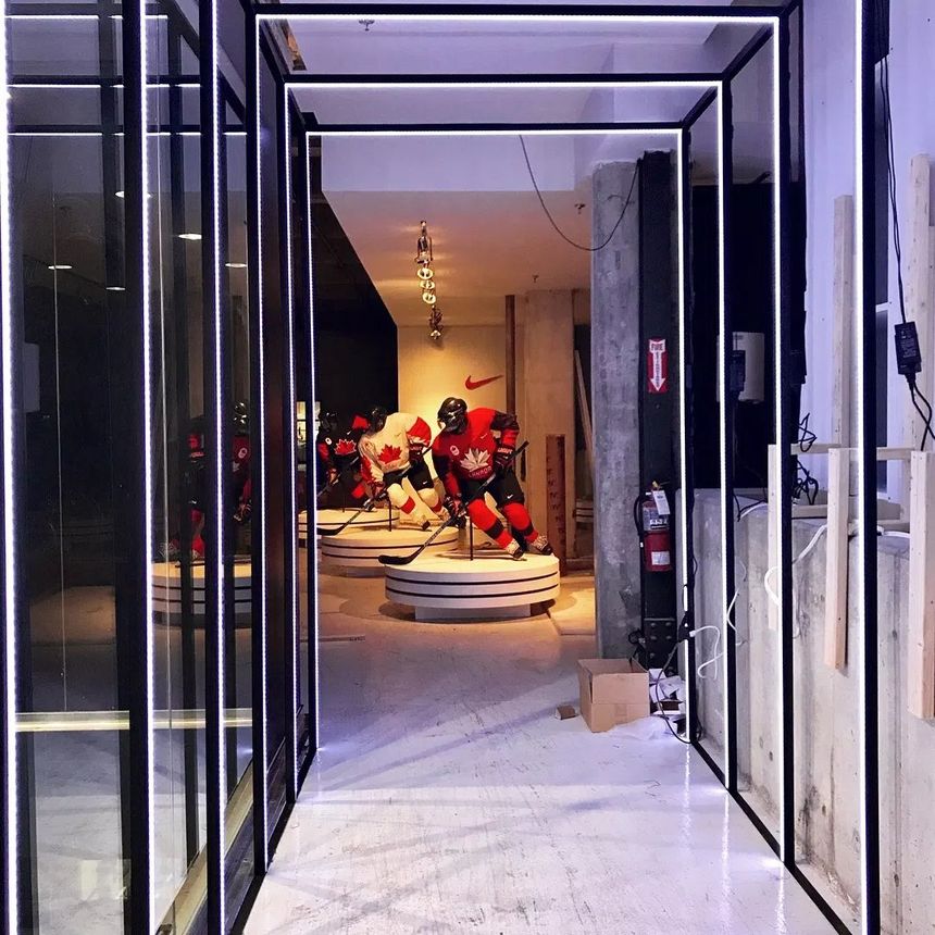Custom black steel and glass partition system with integrated linear LED lighting, built for a commercial retail interior.
