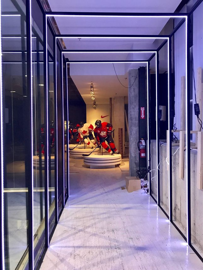 Custom black steel and glass partition framing with integrated linear lighting for a commercial retail fit-out.