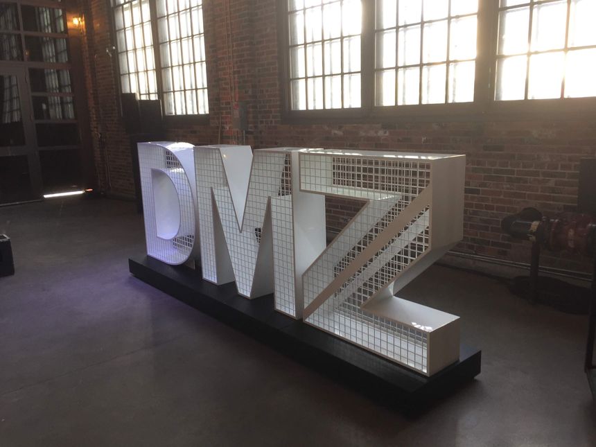 Custom dimensional steel lettering shown installed in a brick-and-timber venue.