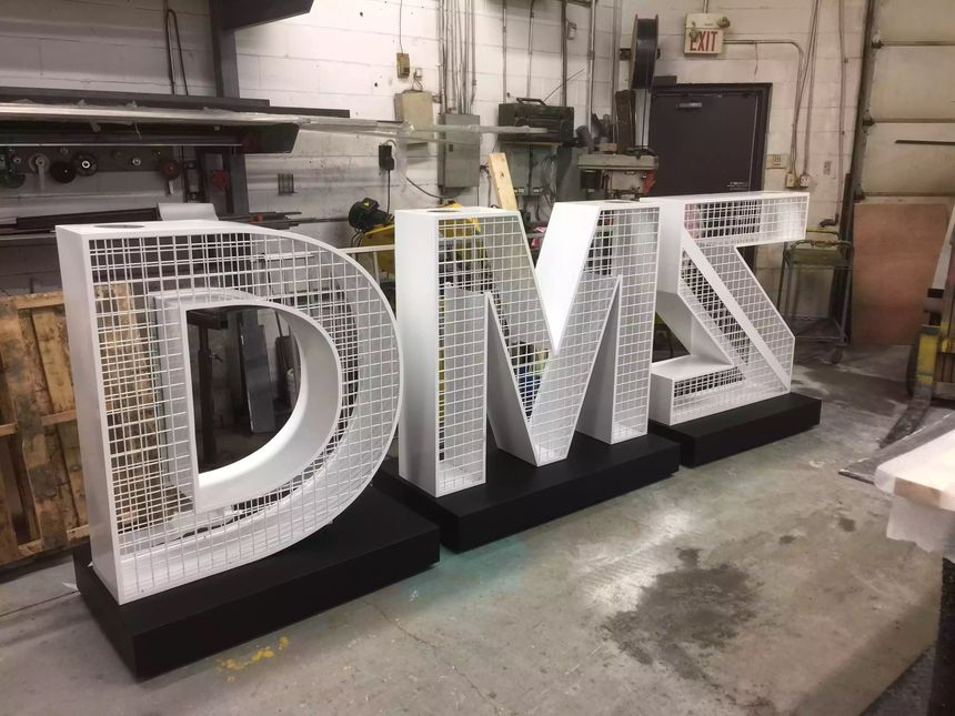 Custom large-format dimensional letters fabricated in steel with mesh detailing and powder-coated bases, built to spec in our shop.
