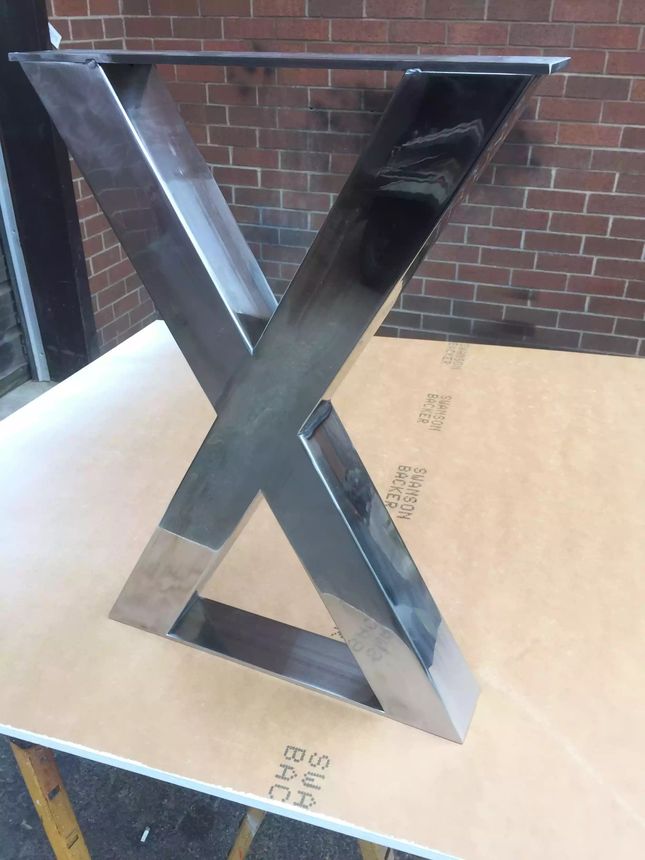 Custom X-form steel table base with a hand-polished mirror finish.