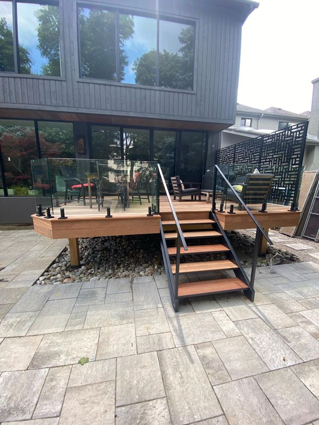 Modern backyard deck with frameless glass railing and steel-framed staircase