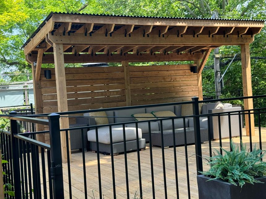 Private deck with black metal railing and cedar pergola lounge