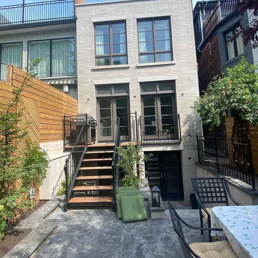 Black steel deck railing paired with an open-riser staircase and wood treads on a city townhome.