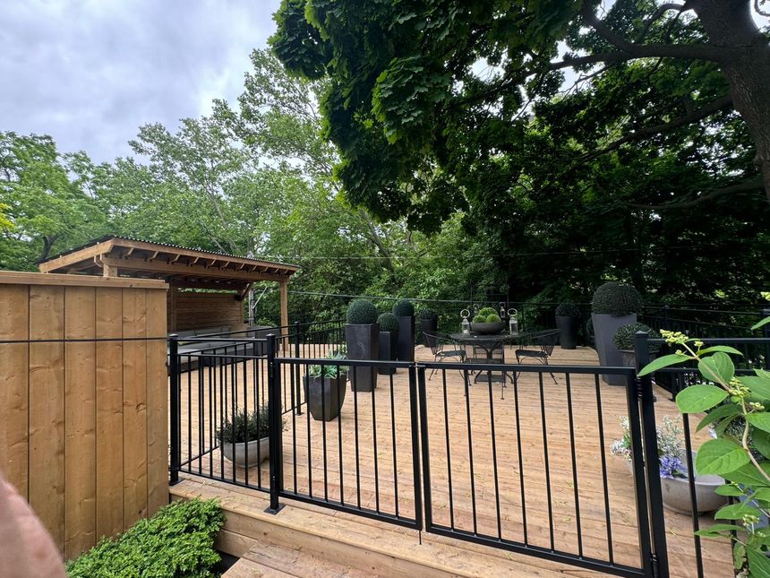Black metal railing enclosing a landscaped backyard deck
