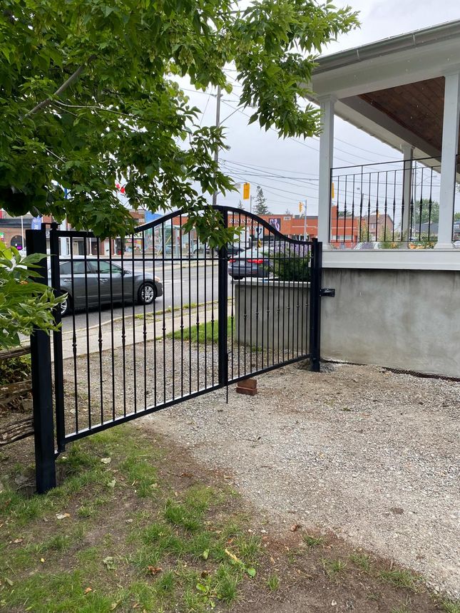Custom wrought-iron double swing driveway gate with arched top rail and classic spear-tipped pickets