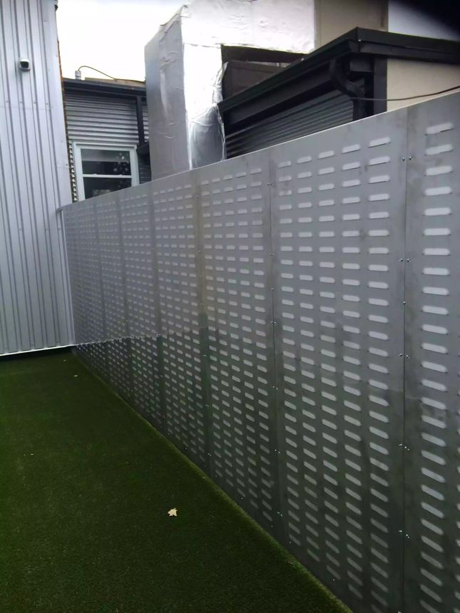 Custom galvanized steel privacy screen with a slotted perforation pattern, fabricated for a rooftop terrace installation.