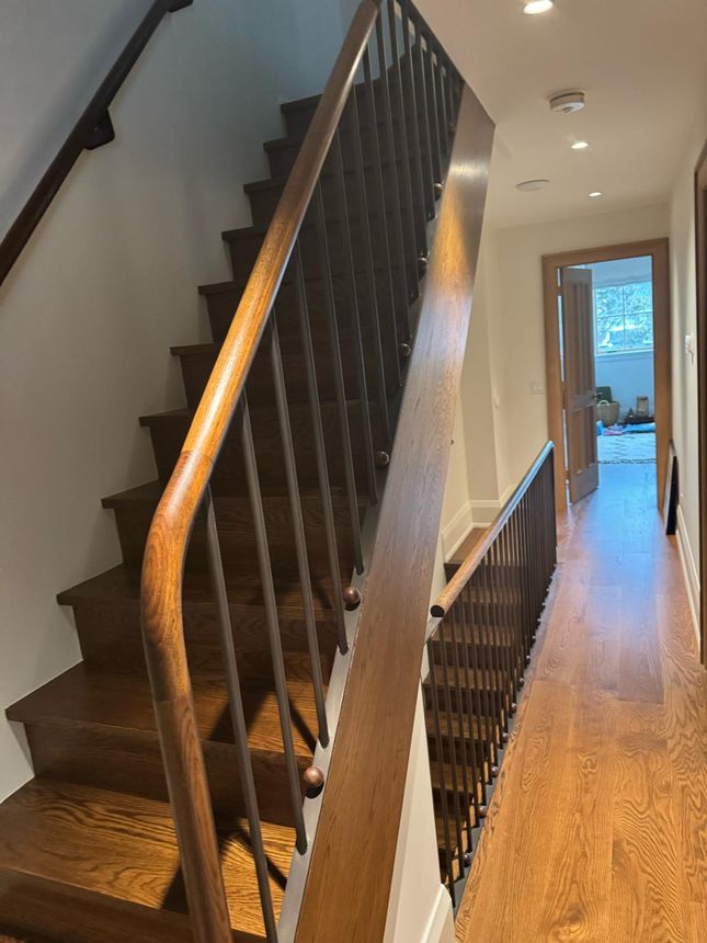 Custom interior stair railing with steel balusters and a hand-shaped wood rail and volute