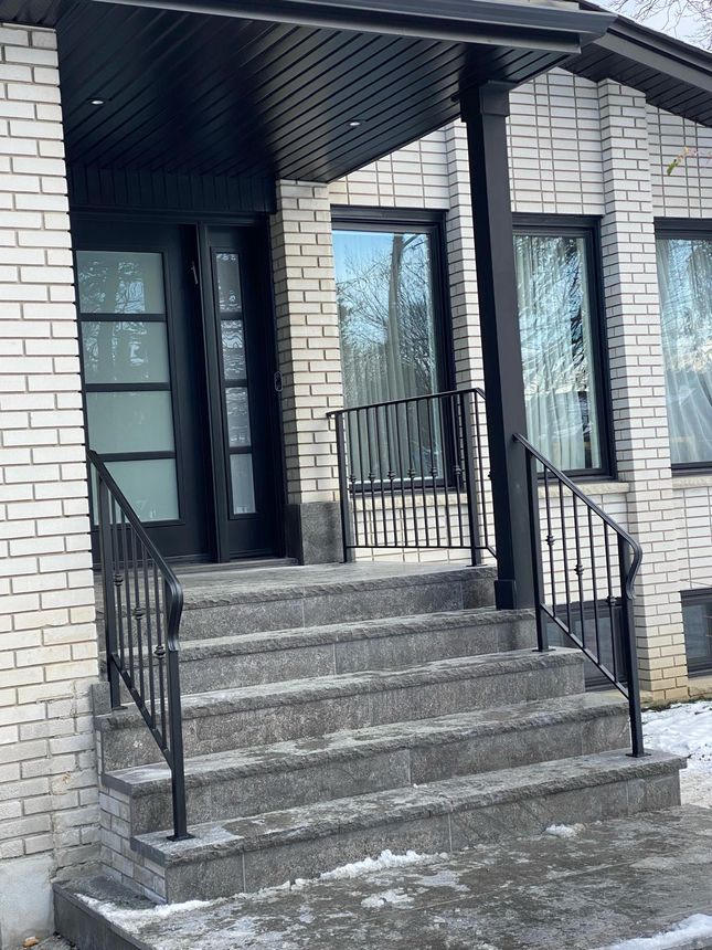 Matching wrought-iron entrance railings on a wide stone porch staircase