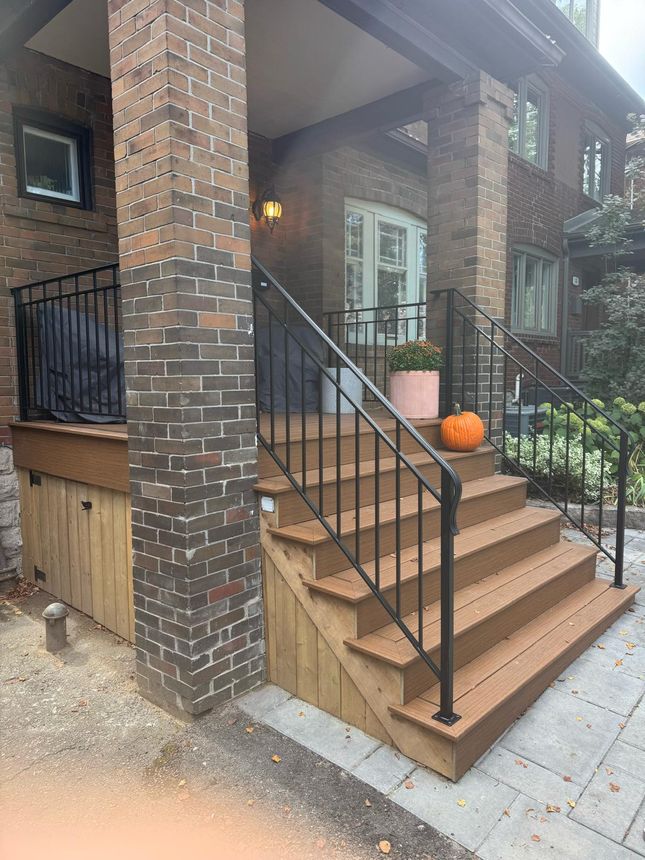 Custom wrought-iron exterior step handrail on a brick-and-composite front porch