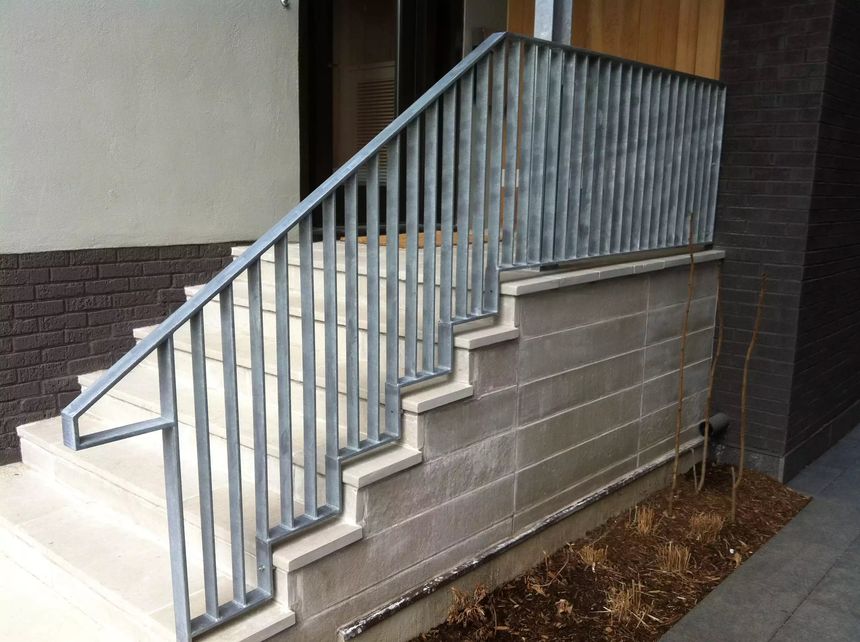 Galvanized steel exterior stair railing with clean vertical pickets, installed over stone steps.