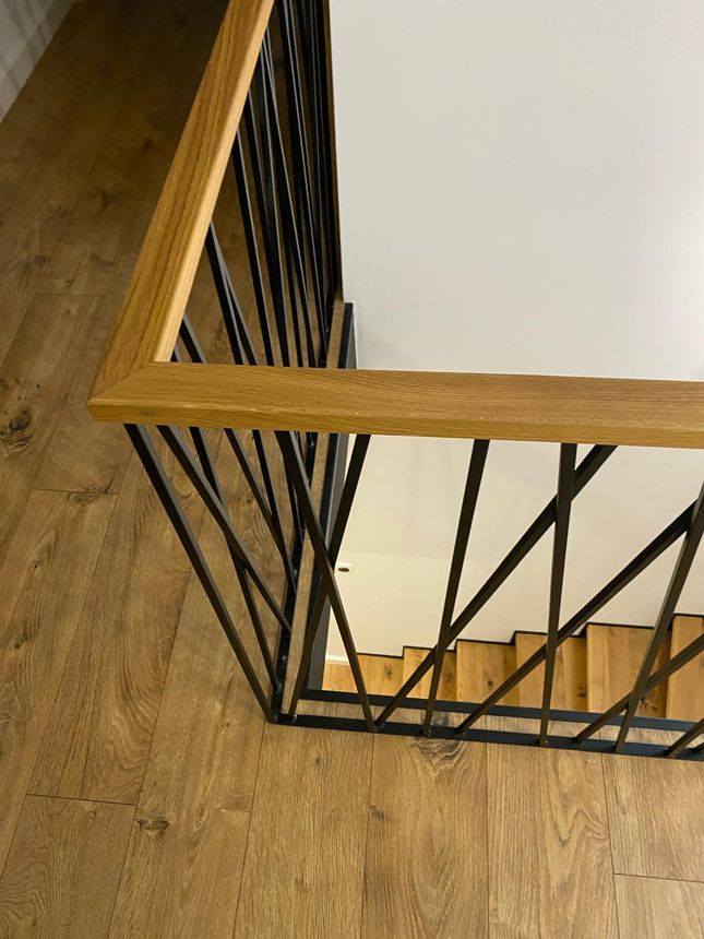 Custom interior stair railing with a wood-capped handrail and geometric iron pickets