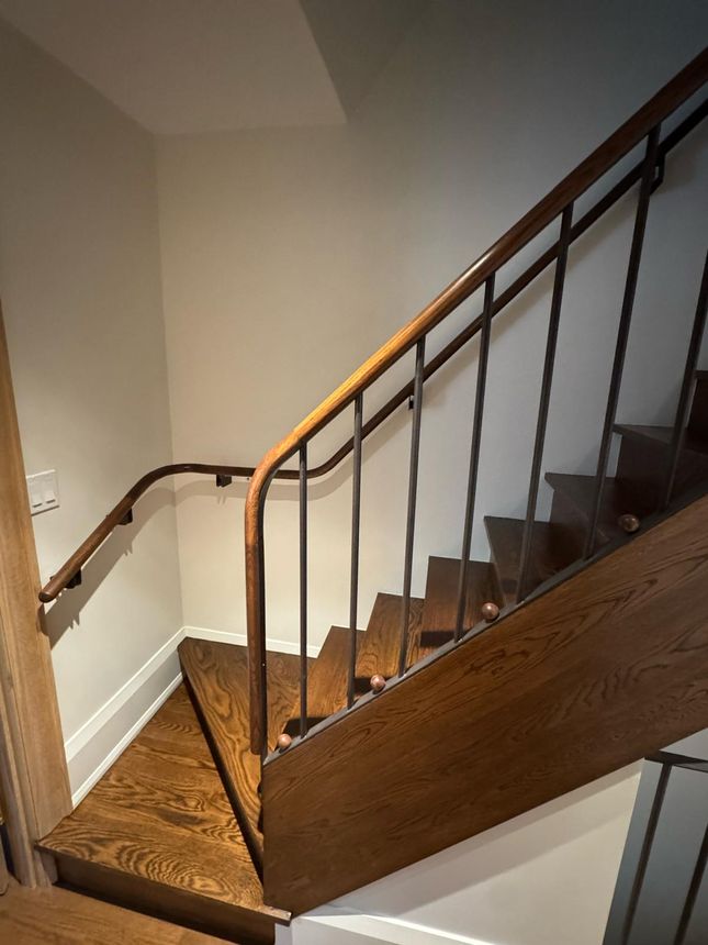 Custom interior staircase railing with curved wood handrail transitions and steel balusters