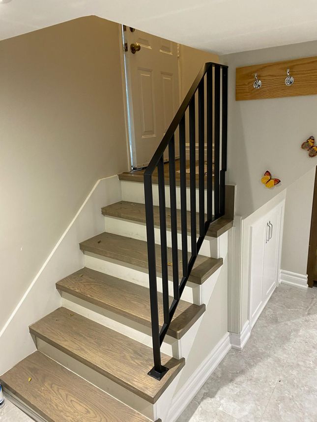 Custom black steel stair railing with clean square balusters paired with hardwood treads