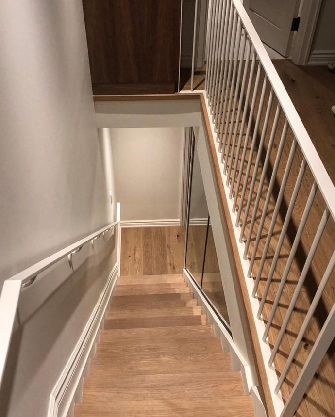 Interior staircase railing with white powder-coated metal balusters and a glass panel section