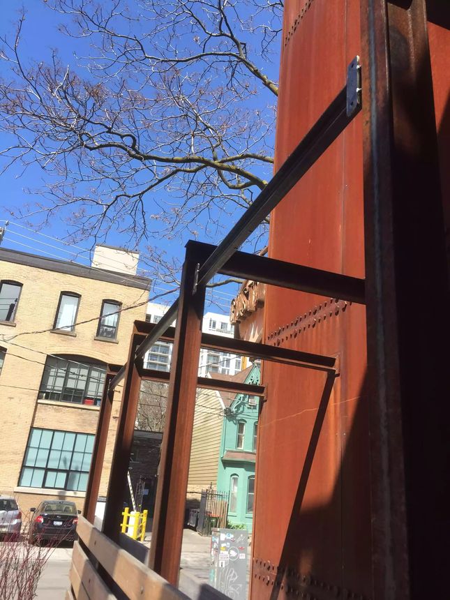 Structural steel framing and riveted weathering-steel panels brought together on a streetside installation.