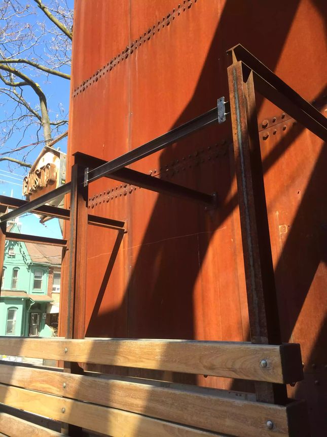Custom structural steel framing paired with a Corten steel wall and hardwood seating.